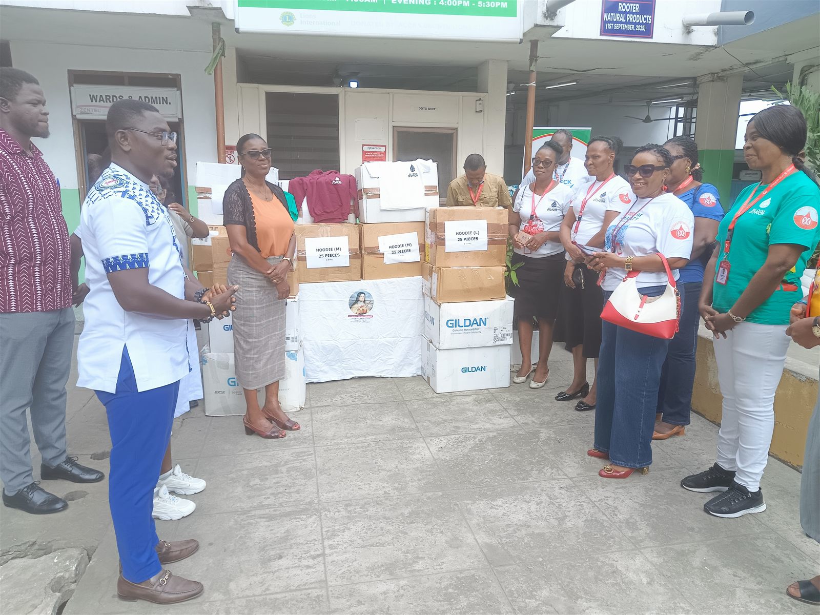 Hospital and NBS representatives gather beside boxes of donated children’s clothing during the presentation.